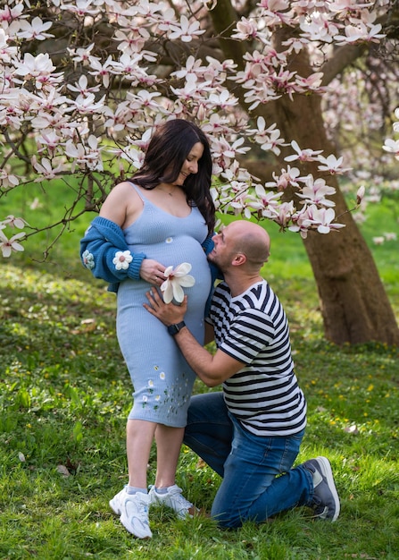 Photo a caring man puts his ear to his pregnant wifes belly and listens to the babys heartbeat