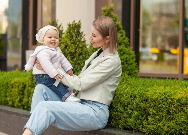 Una madre moderna ed elegante e premurosa tiene la figlia tra le braccia in una città stile di vita materno