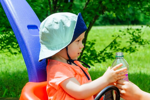 Caring mother gives daughter drink water bottles summer park