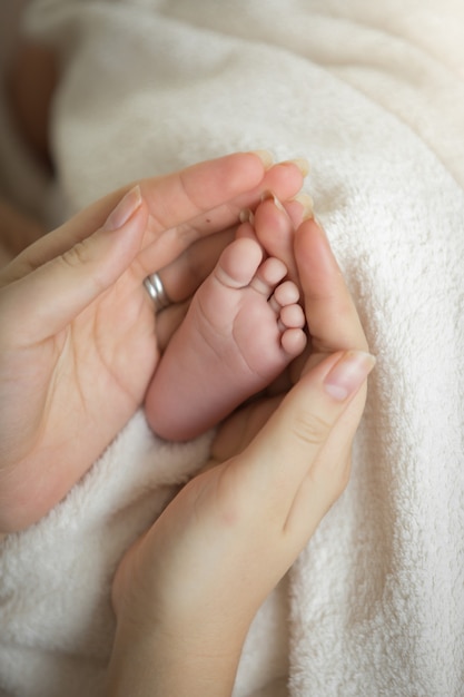 caring mother holding newborn baby little feet