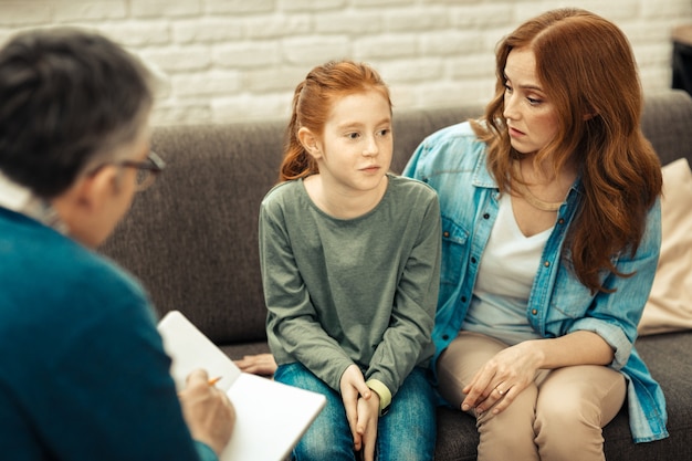 Photo caring mother. nice young woman looking at her daughter while listening to her