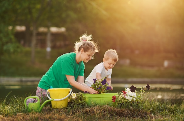 Caring for nature. Mother And Son Planting Seedling In Ground On Allotment on the river bank. Botanical and ecology concept.	