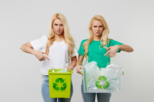 自然を気遣う。緑のTシャツを着た若い女性がペットボトルとゴミの入った箱を抱えています。ボランティアがゴミをまとめてリサイクルに運びました。