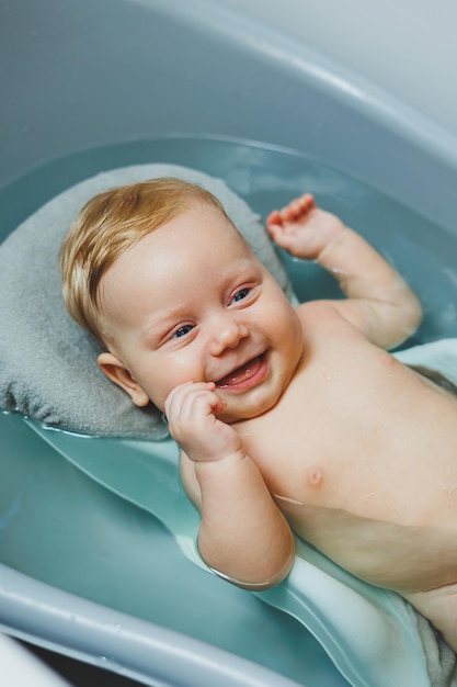 Foto prendersi cura di un neonato, fare il bagno al bambino, fare il bagno al bambino nella vasca da bagno, fare il primo bagno del bambino.