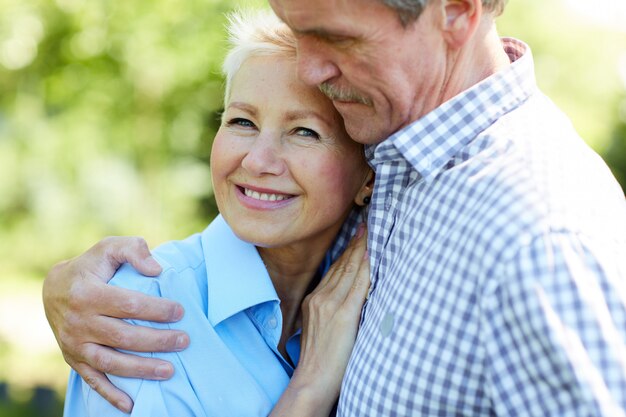 Caring senior couple embracing in park