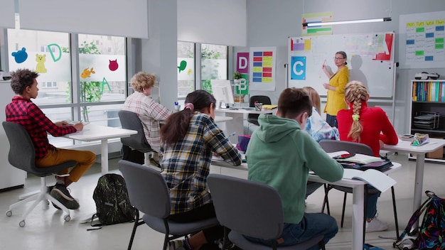 Caring teacher explains lesson to classroom full of diverse children