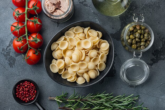 Carlofortina pasta met tonijn ingrediënten, op grijze tafel, bovenaanzicht