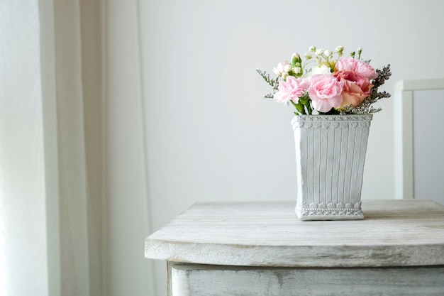 Fiore del garofano in vaso del cemento sul gabinetto d'annata alla camera da letto