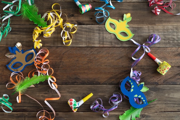 Carnaval decoratie op rustieke houten achtergrond met kopie ruimte in het midden. Maskers met linten en andere carnavalselementen.