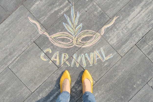 Carnaval op grijze stoep met vrouwenbenen wordt geschreven in gele schoenen die