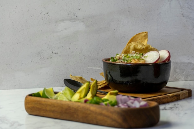 Фото Мексиканская еда carne en su jugo включает лук, редис, говядину и кукурузные тостады.