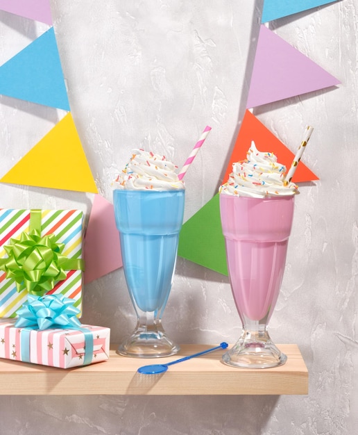 Carnival colorful celebrate garland with flags Delicious sweet creamy desserts in glasses on the table Beautiful gifts with gift bows on a gray concrete background