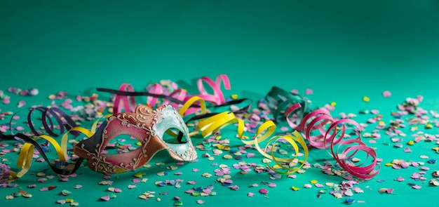 Carnival mask streamers and confetti on bright green background