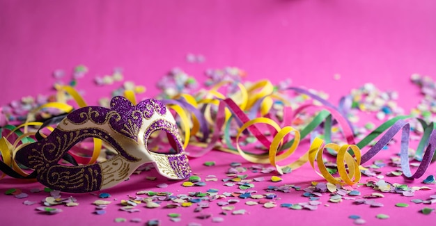 Carnival mask streamers and confetti on pink background