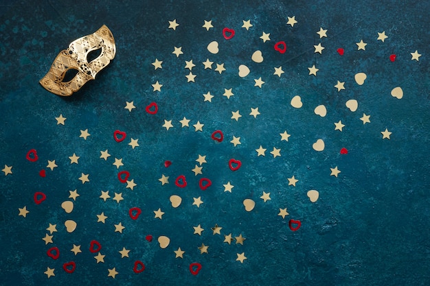 Carnival masks and gold glitter confetti. top view, close up on blue background