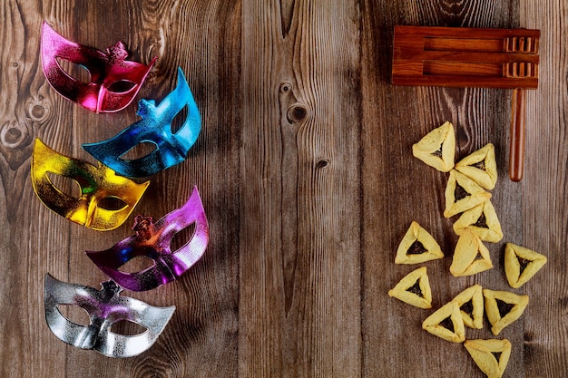 Carnival masks on wooden background with noisemaker . Jewish holiday Purim.