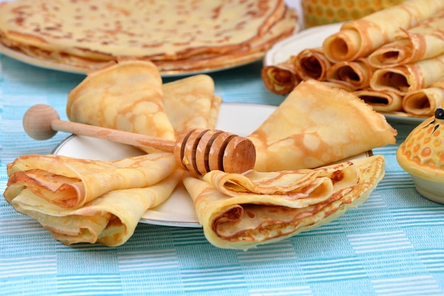 Carnival thin pancakes with honey and honey dipper on a plate