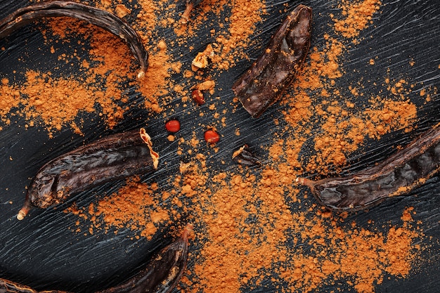 Carob fruit with powder on black surface