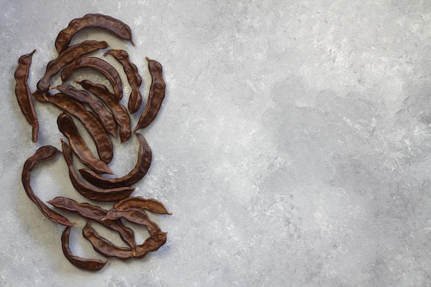 Carob Healthy organic sweet carob pods on gray wooden background closeup