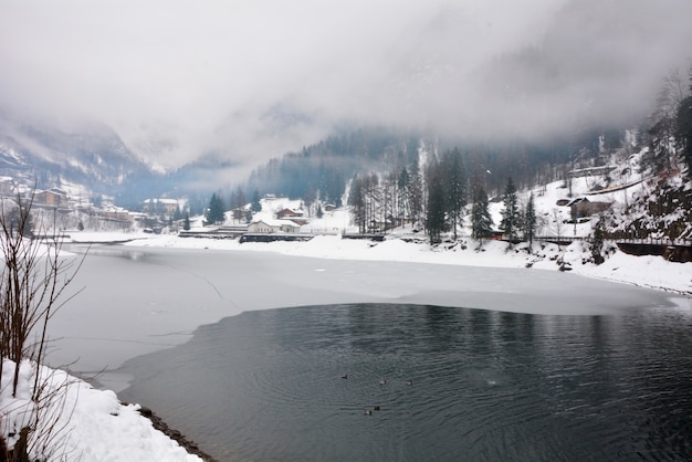 Paesaggio di inverno del lago e delle montagne del villaggio dell'italia di carona