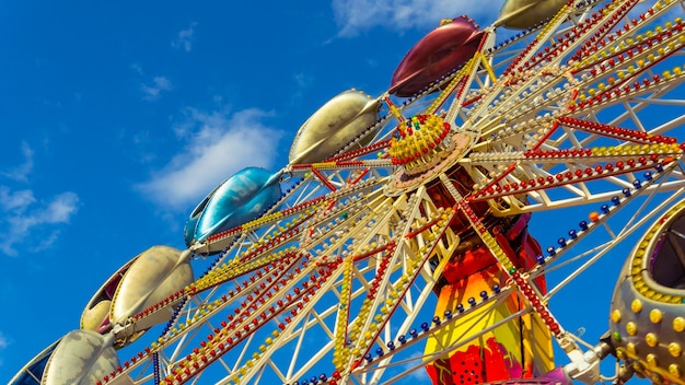 The Carousel is spinning against the blue sky in amusement park, close-up