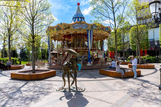 A carousel in a park with trees and people on it