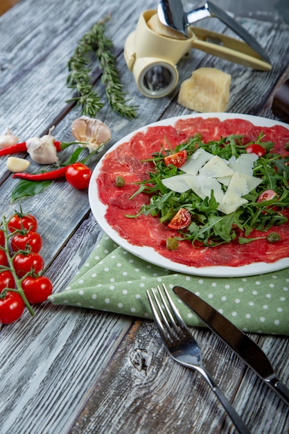 carpaccio meat with arugula and slices of parmesan cheese