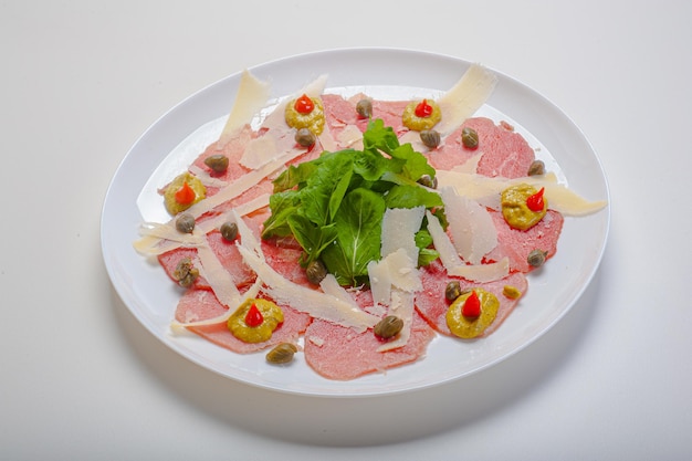 Carpaccio van filet geserveerd met rucola en kappertjes