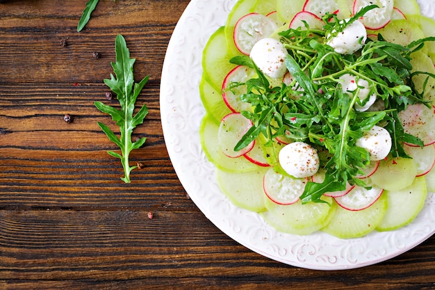 Carpaccio van radijs met rucola, mozzarella en saus. Gezond eten. Daikon salade. Plat leggen. Bovenaanzicht