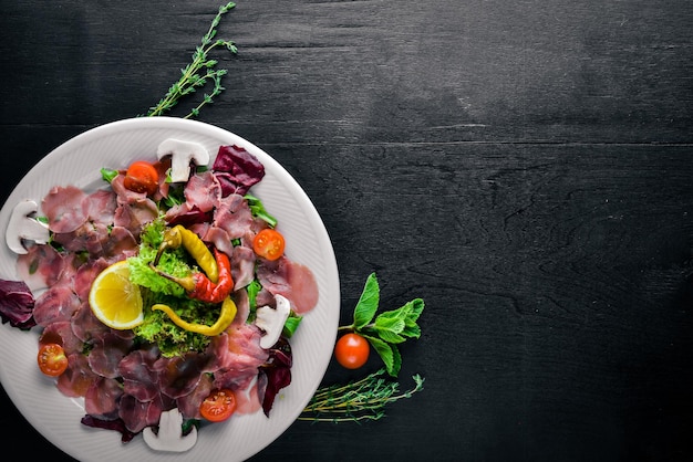 Carpaccio van rundvlees, groenten, kaas, kruiden, op houten achtergrond. Bovenaanzicht. Vrije ruimte