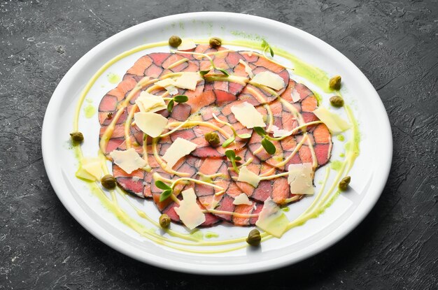 Carpaccio van zalm en tonijn met saus en kaas op een wit bord Bovenaanzicht Rustiek