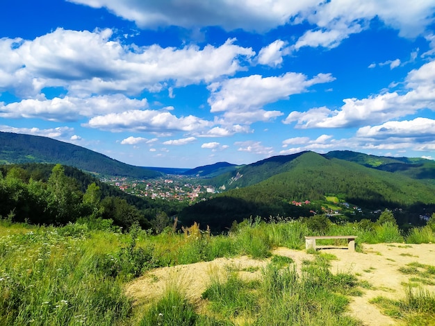 Carpathian landscape with cloudy sky A wooden bench on a green meadow in mountains near forest Lifestyle in the Carpathian region Ecology protection concept Explore the beauty of the world