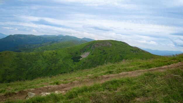 Carpathian Mountains Panorama of green hills in summer mountains Hazy green mountain forest under blue sky