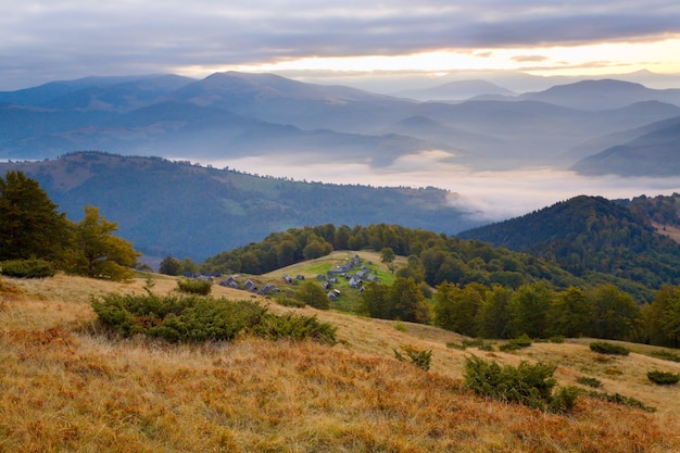 Carpathian Mountains (Ukraine) autumn landscape with cattle-breeding farm and country road.