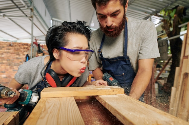 Falegname che soffia via la polvere di legno