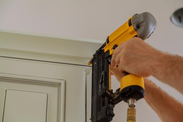 Carpenter brad using nail gun to Crown Moulding on kitchen cabinets framing trim