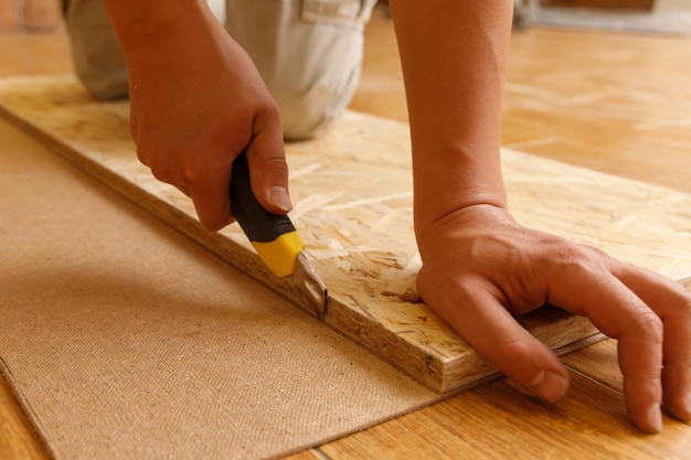 Photo carpenter cuts fiberboard with a mounting knife using osb