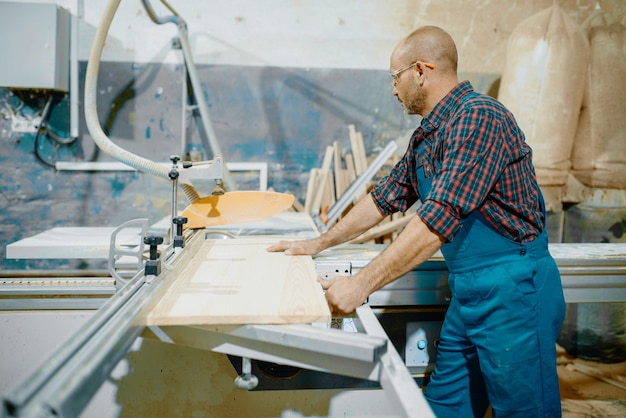 Il carpentiere taglia tavola di legno su sega circolare, lavorazione del legno, industria del legname, falegnameria.