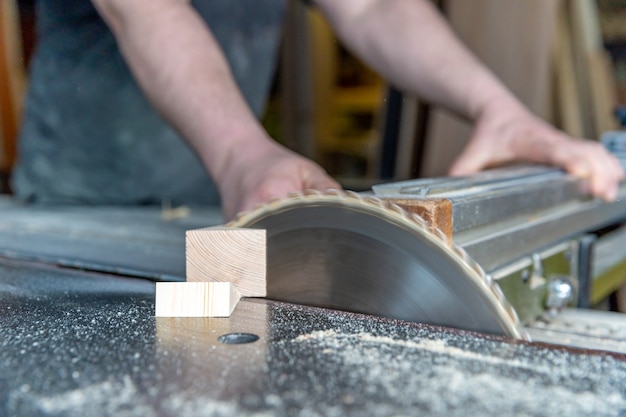 Carpenter cuts wooden plank on circular saw