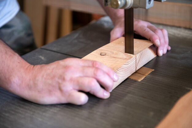 Carpenter cutting a block of wood on a band saw