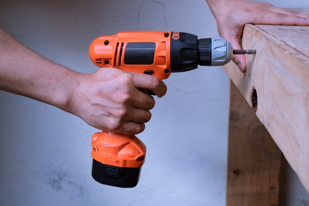 Foto il carpentiere fa un buco con un trapano elettrico