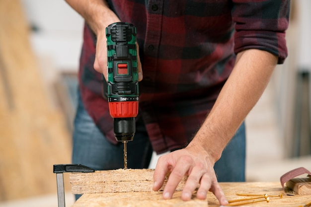 Carpenter drills a hole with an electrical drill