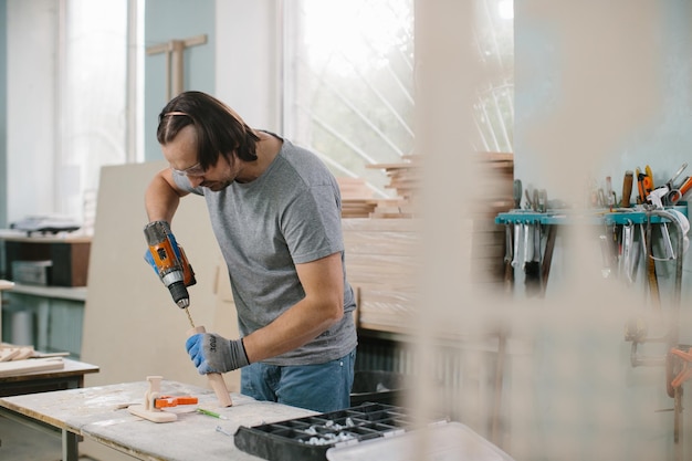 Carpenter drills a hole with an electrical drill