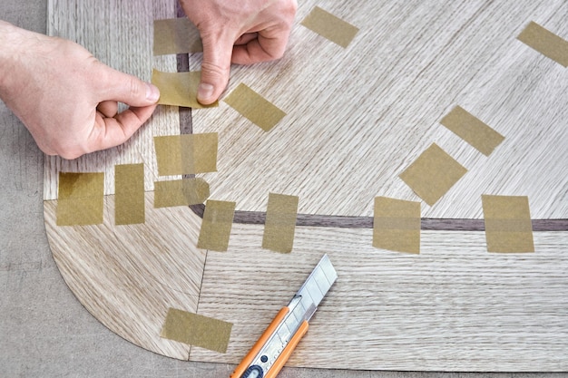 Carpenter gewrichten fineer met tape voor tafelblad van eettafel met geometrische patroon close-up