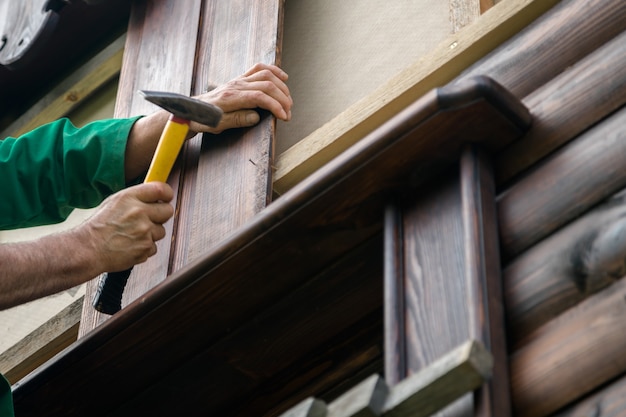 Carpenter handyman hammering a nail in wooden board.