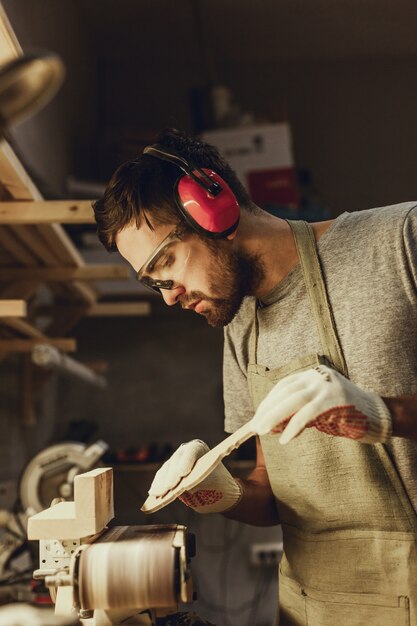 Carpenter holding wooden part near sander