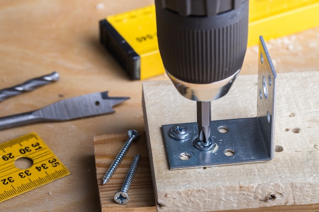 Carpenter holds a cordless screwdriver and wraps the screw