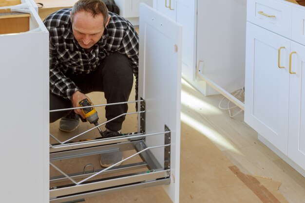 A carpenter is building a drawers garbage bin in the kitchen