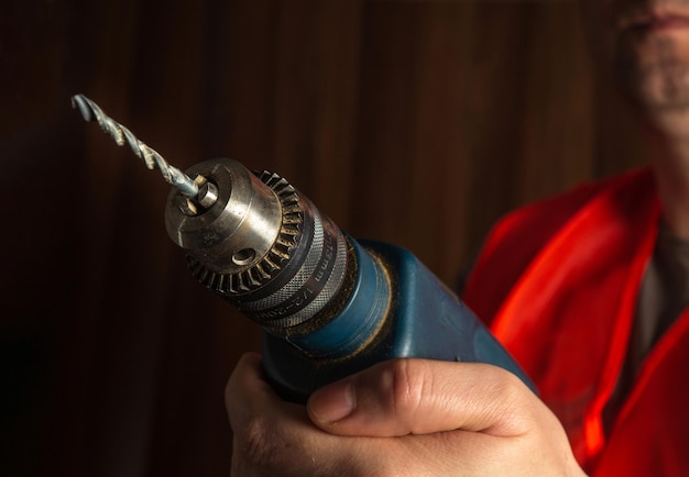 Carpenter іs hand holds an electric drill close-up during carpentry work. Working environment in a carpentry workshop