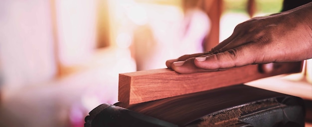 A carpenter is sanding the wood with a sandpaper.